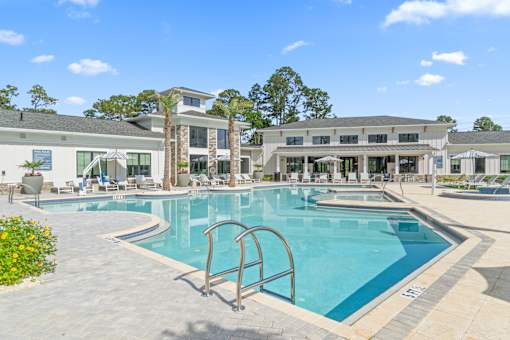A large swimming pool with a diving board in front of a building.