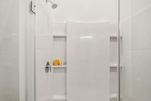 A white bathroom with a shower head and a towel rack at The Stadler Luxury Apartments, Florida 34210