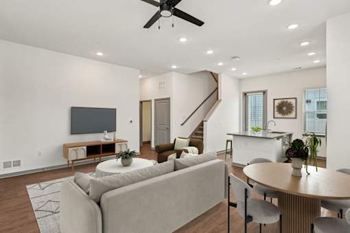 A living room with a grey couch, a television, a coffee table, and a staircase. at The Sophia, Venice, FL