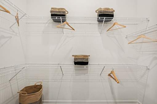 A white wire shelving unit with three shelves and four hangers at The Stadler Luxury Apartments, Florida 34210