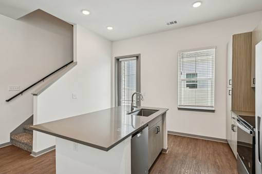 A modern kitchen with a stainless steel sink and wooden floors. at The Sophia, Venice, FL