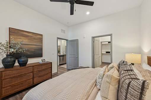 A bedroom with a bed, dresser, and ceiling fan.