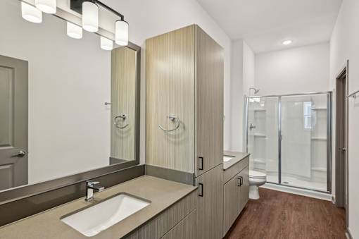 A modern bathroom with a sink, mirror, and wooden cabinets. at The Sophia, Venice, FL