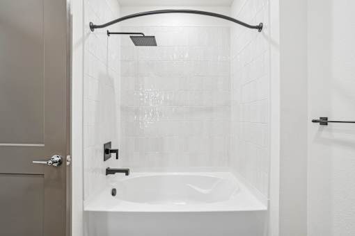 A white bathroom with a white tub and a white shower curtain.