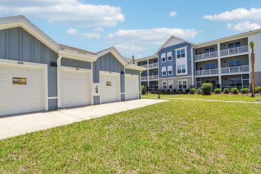 Private garages with driveways and apartment community buildings at Velara Luxury Apartments, Florida