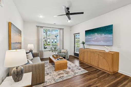 Living room with wood media console and ocean artwork at Velara Luxury Apartments, Ponte Vedra Beach, FL 32081