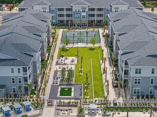 A large grassy area surrounded by buildings with a basketball court in the middle.