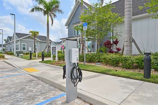 A charging station for electric vehicles is located on a sidewalk in front of a building. at The Sophia, Venice, FL