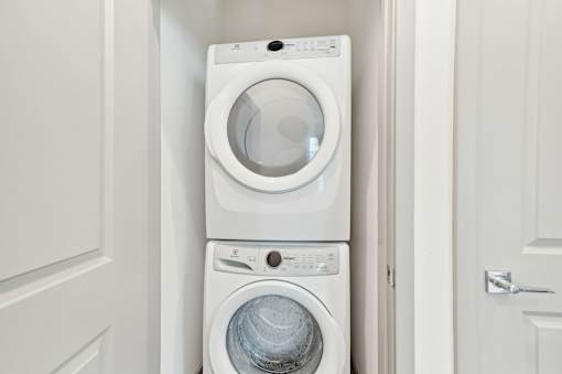 A white washing machine and dryer in a small laundry room at The Hadley - North Port, FL Apartments, North Port, FL, 34287