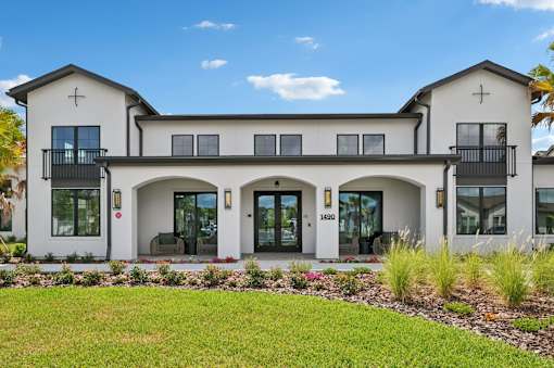 A white two-story house with a balcony on the second floor. at The Hadley - North Port, FL Apartments, North Port, FL, 34287