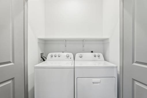 Two white front loading washing machines in a laundry room.