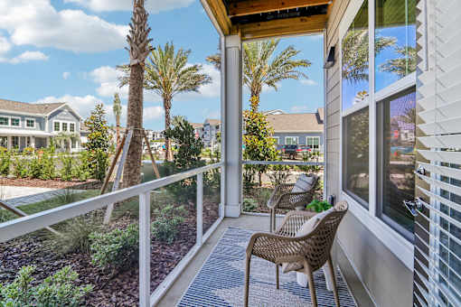 Covered balcony with seating overlooking landscaped courtyard at Velara Luxury Apartments, Ponte Vedra Beach, 32081