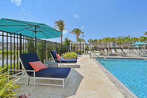 A pool area with chairs and a blue umbrella. at The Sophia, Venice, FL