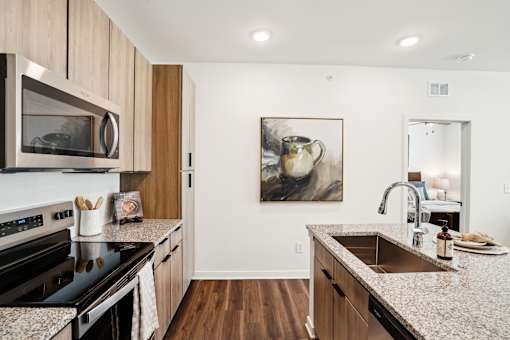 A kitchen with a granite counter top and wooden cabinets. at The Pullman Luxury Apartments, Georgia, 30349
