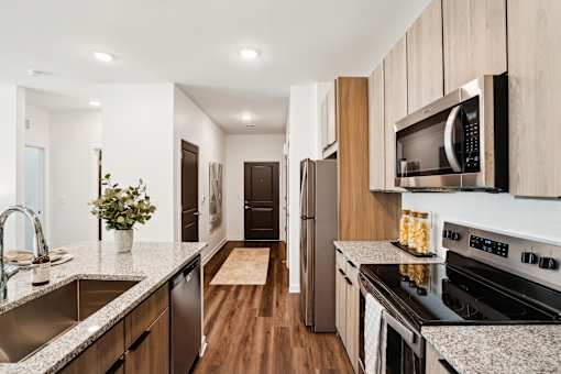 A modern kitchen with wooden cabinets and stainless steel appliances. at The Pullman Luxury Apartments, Atlanta, Georgia