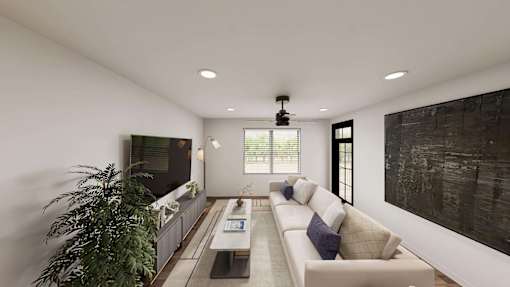 A modern living room with a large couch, a flat screen TV, and a potted plant.