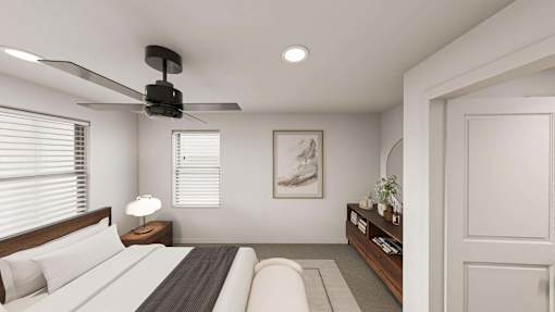 A bedroom with a bed, a ceiling fan, and a nightstand with a lamp.