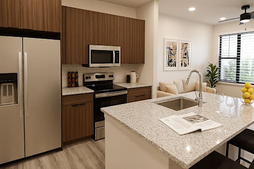 A modern kitchen with a granite countertop and stainless steel appliances at The Stadler Luxury Apartments, Bradenton, Florida