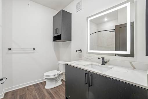 A bathroom with a toilet, sink, and mirror.
