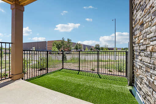 A view from a patio looking out to a grassy area and a building.