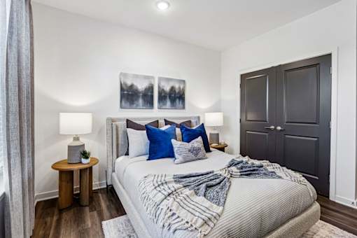 A bedroom with a bed, two lamps, and a painting on the wall.