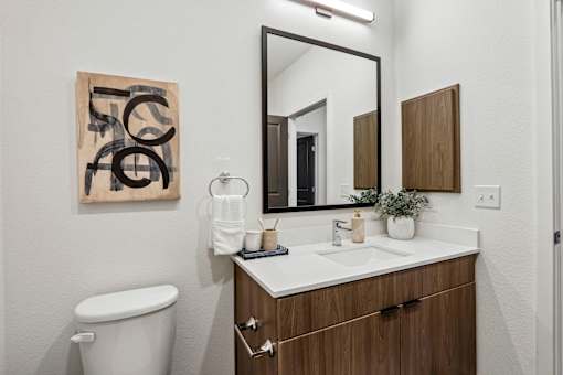 A bathroom with a toilet, sink, and a mirror.