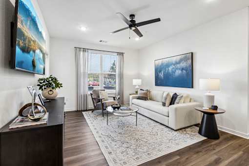 A living room with a white couch, a coffee table, and a painting on the wall.