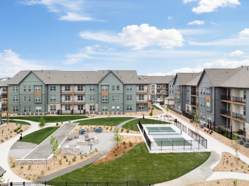 an exterior view of an apartment complex with a tennis court and a pool at Notch66, Longmont, Colorado