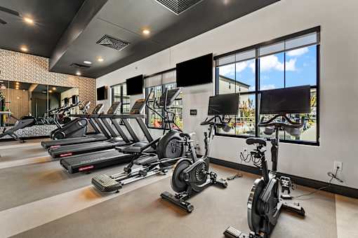 A gym with treadmills, elliptical machines, and stationary bikes.