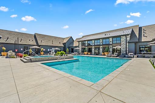 A large outdoor swimming pool with a concrete floor and a building in the background.