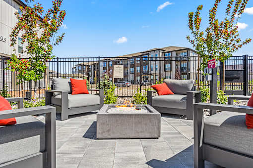 A patio with grey chairs and a concrete table.