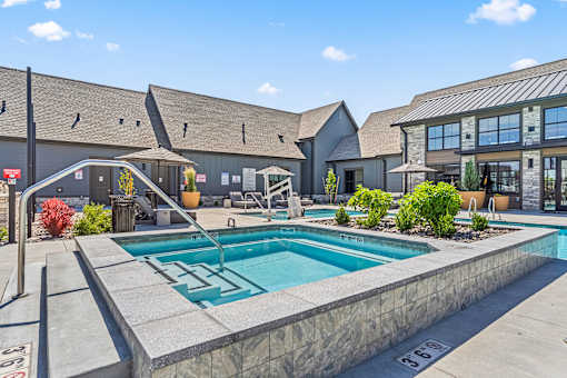 A pool surrounded by a stone wall with a building in the background.