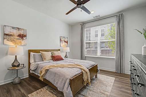 A bedroom with a bed, a ceiling fan, and two lamps.