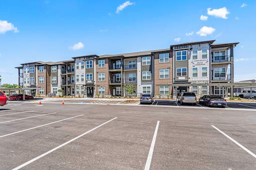 A parking lot in front of a multi-story apartment building.