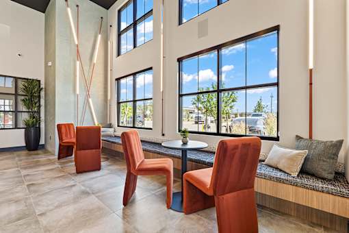 A room with orange chairs and a bench with a table and a plant.