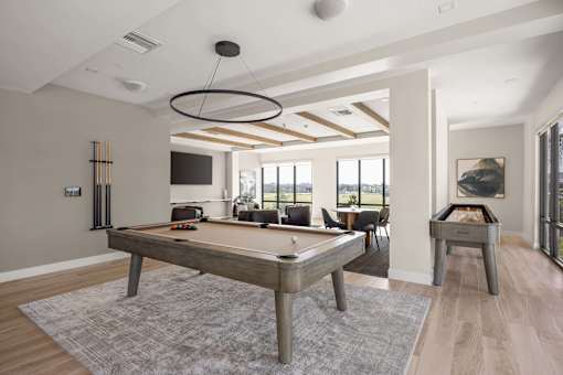 A pool table is in the middle of a room with a grey rug.