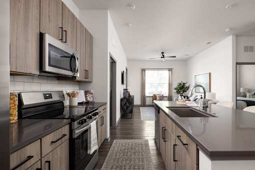 A modern kitchen with dark countertops and wooden cabinets.