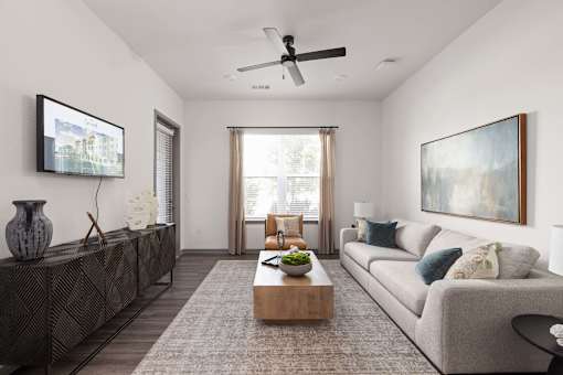 A living room with a grey couch, a coffee table, and a painting on the wall.