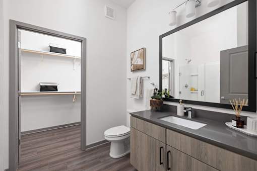 A bathroom with a toilet, sink, and mirror.