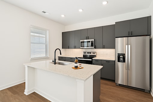 A modern kitchen with a white island and stainless steel appliances.