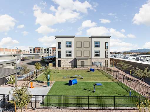 a park with grass and a playground in front of a building at The Maddox Luxury Apartment Homes, Buckeye, AZ, 85326
