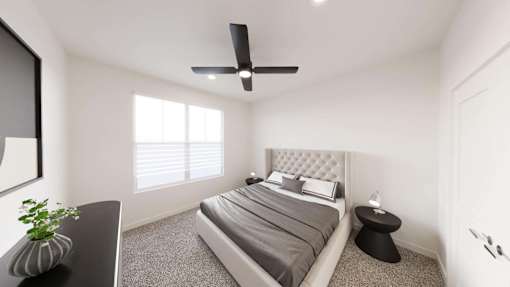 A bedroom with a bed, a ceiling fan, and a small table with a plant on it.