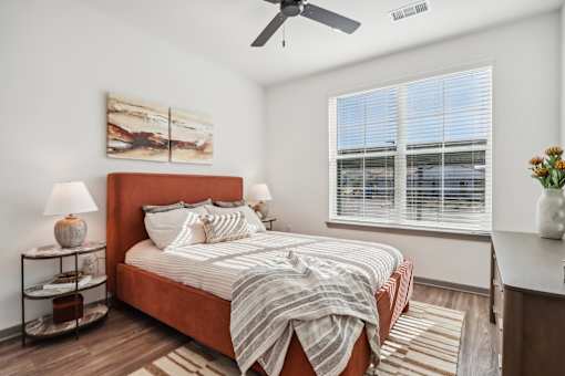 A bedroom with a bed, a ceiling fan, and a painting on the wall at The Pullman Luxury Apartment Homes, Georgia 30349