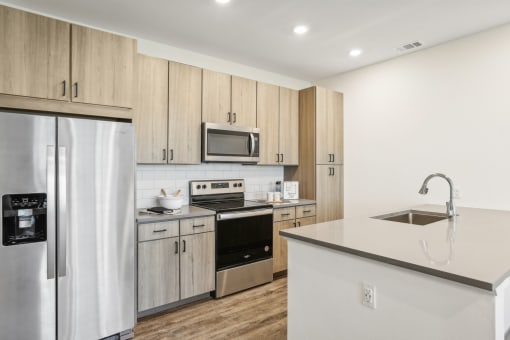 a kitchen with stainless steel appliances and wooden cabinets at Drift, Daytona Beach, FL, 32117
