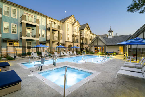 a swimming pool with chairs and umbrellas in front of apartment buildings  at Oakbrook Townhomes, Franklin, Tennessee
