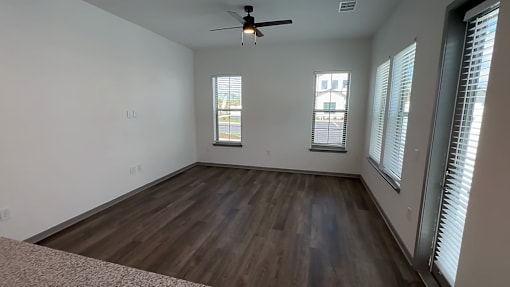 A room with a ceiling fan and wooden flooring.