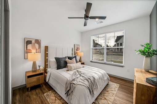 A bedroom with a bed, nightstand, and a ceiling fan at The Levi Luxury Apartments, McDonough, 30253