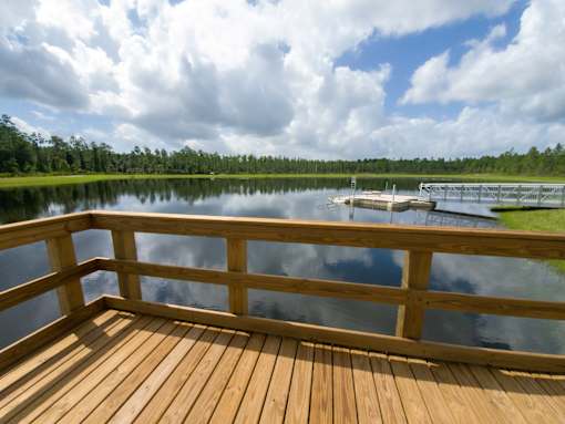 Wooden dock overlooking tranquil pond and tree line at Velara Luxury Apartments, Ponte Vedra Beach