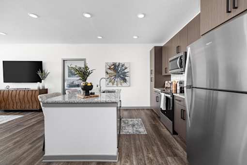 A modern kitchen with a stainless steel refrigerator and wooden flooring.