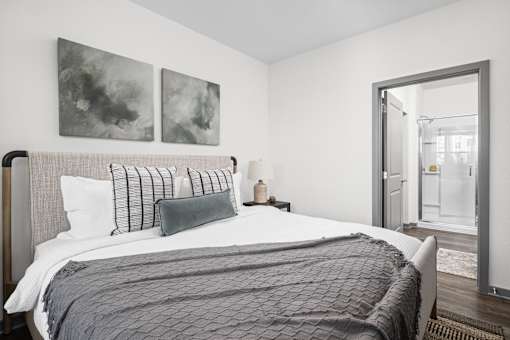 A bedroom with a large bed and two paintings on the wall.